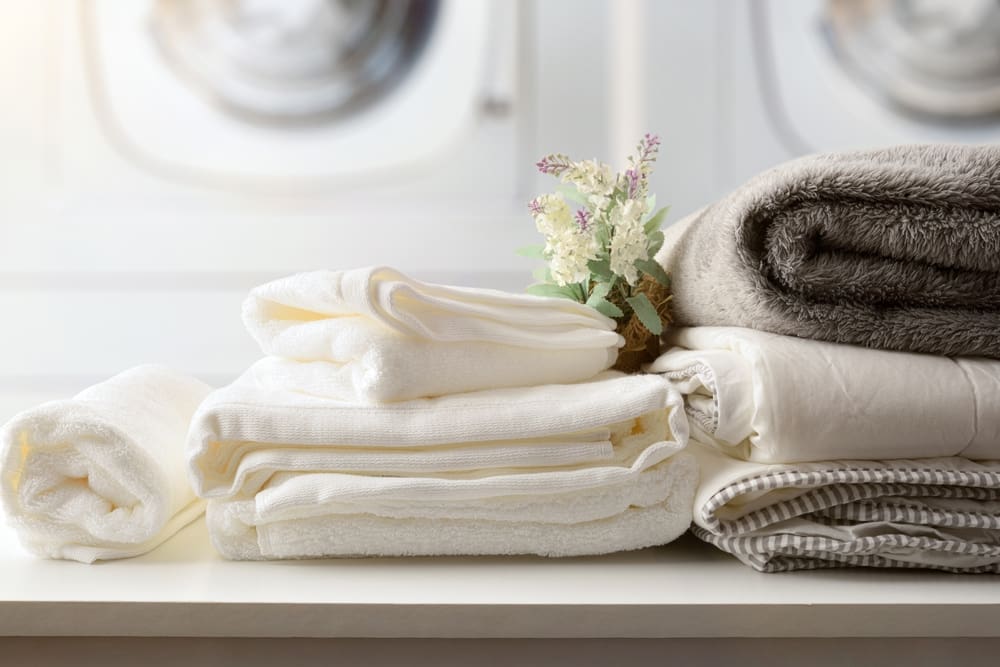 Freshly laundered and neatly folded towels and linens arranged on a table, showcasing the quality of Best Cleaners' Wash and Fold Laundry Service.